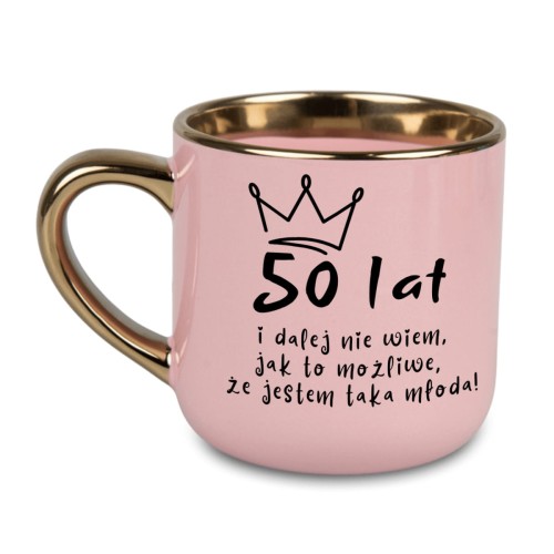 Różowy kubek 400 ml ze złotym uchem i rantem – prezent na 50 urodziny z napisem „50 lat i dalej nie wiem, jak to możliwe, że jestem taka młoda!”