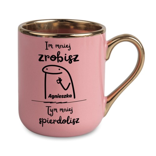 różowy kubek ze złotym uchem i napisem Im mniej zrobisz tym mniej spier...lisz